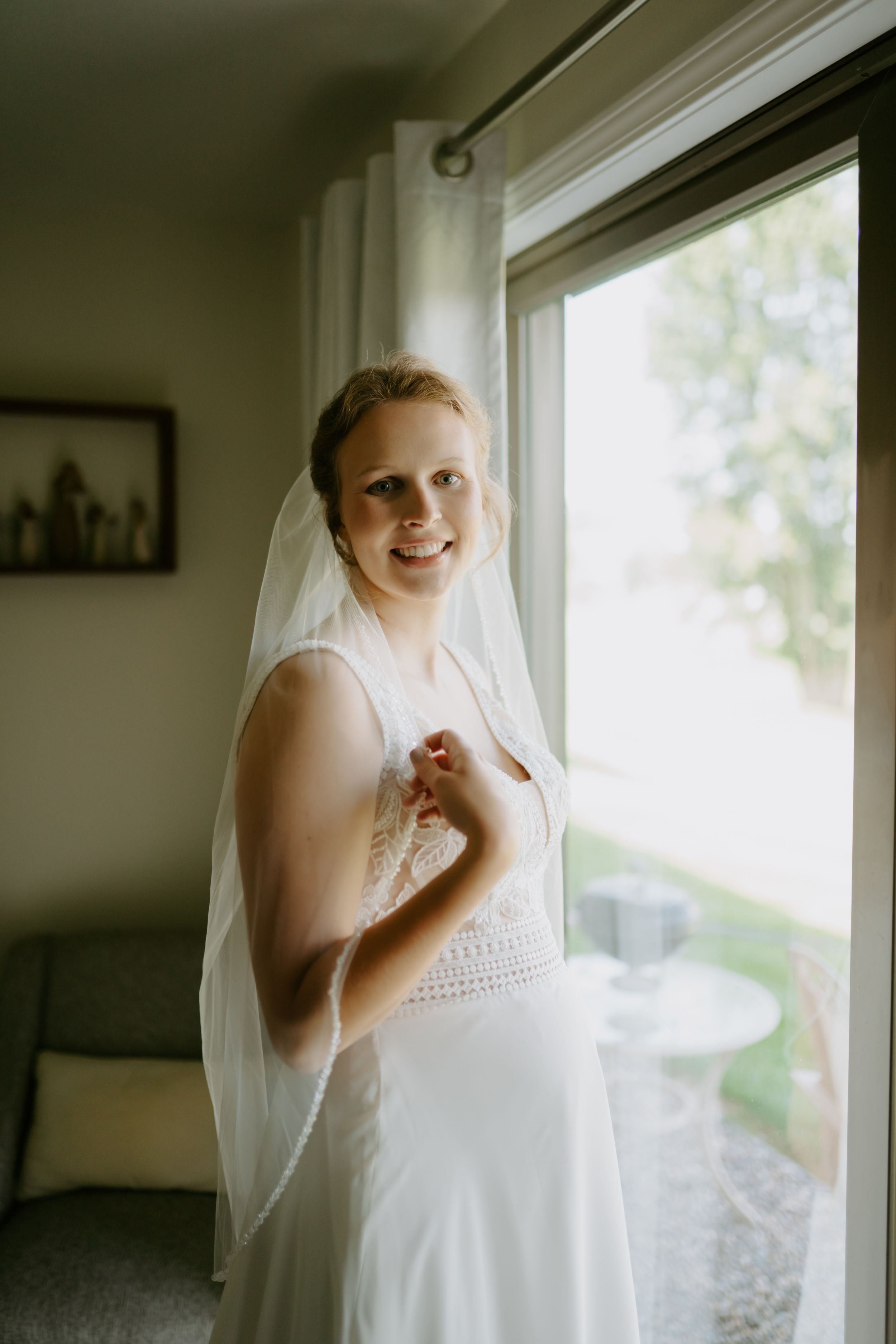 Bridal preparation moments by window in natural light.