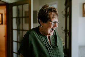 A person in green top expressing joy and laughter in an indoor setting.
