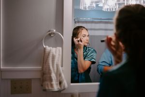Someone applying makeup in bathroom mirror during wedding preparations.
