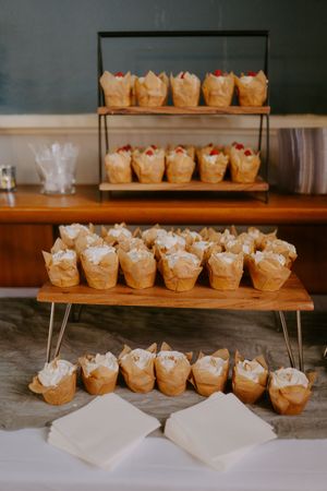 Rows of small desserts arranged on wooden serving boards at a catering display.