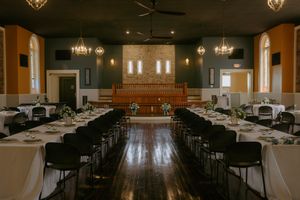 Large banquet hall with rows of tables and chairs under crystal chandeliers.