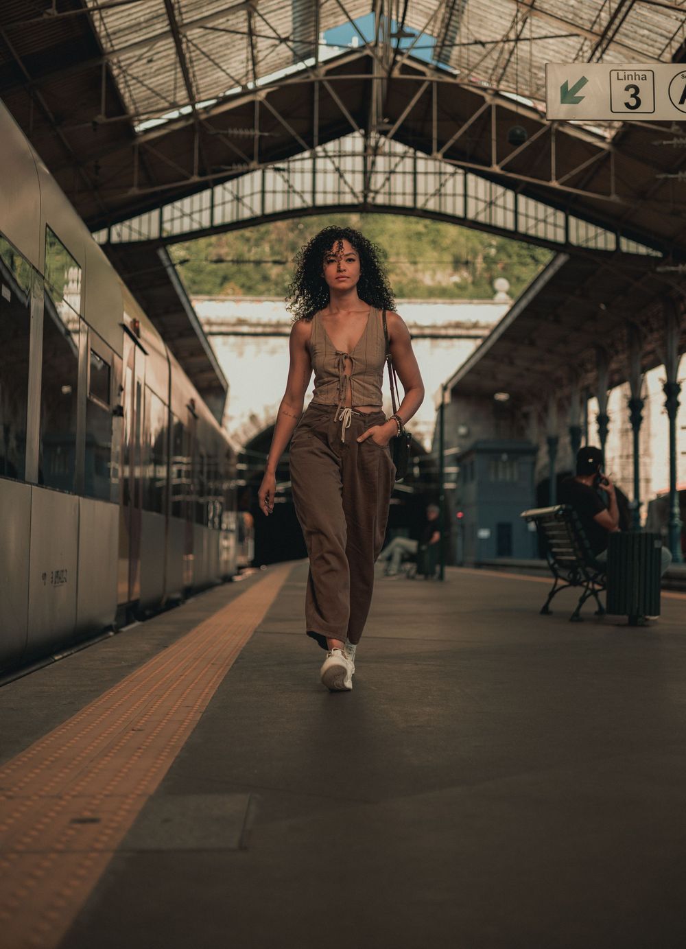 A stylish casual outfit photographed at a train station platform with industrial architecture.