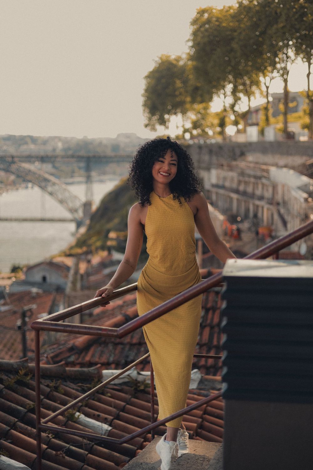 Urban fashion photography on traditional clay tile rooftops with city skyline in background.