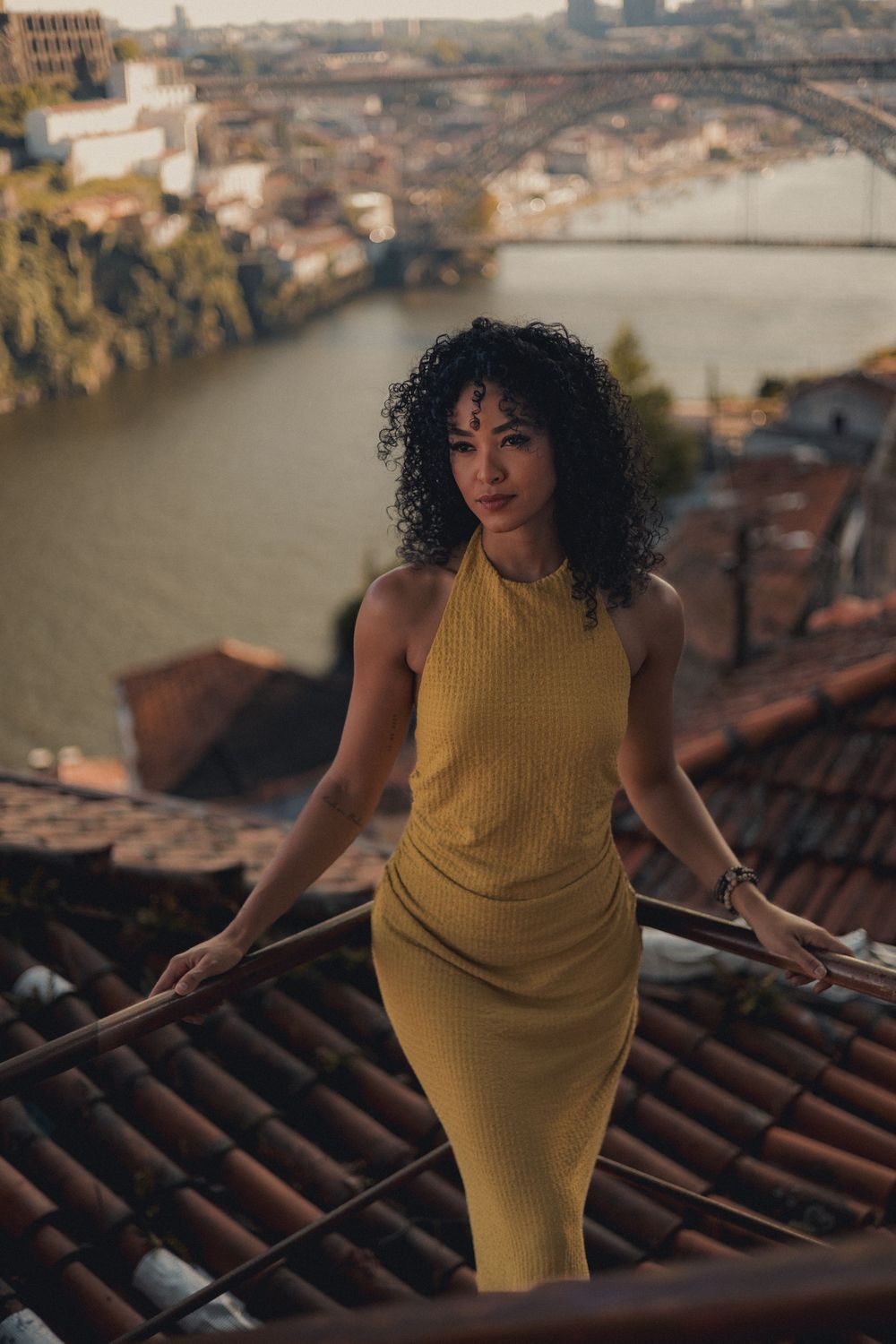 Artistic fashion photography on vintage tiled rooftop with panoramic city views.