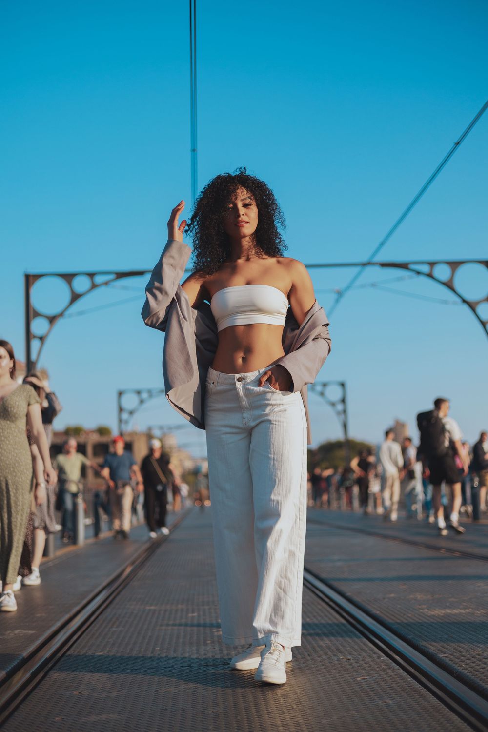 Modern fashion photography on bridge walkway with urban architecture in background.