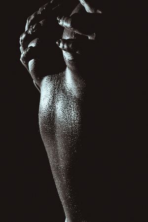 Artistic black and white photograph of a water-covered body with glistening droplets creating a dramatic silhouette.