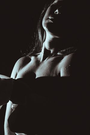 Artistic black and white nude photograph showing dramatic shadows and lighting on skin with head tilted back.