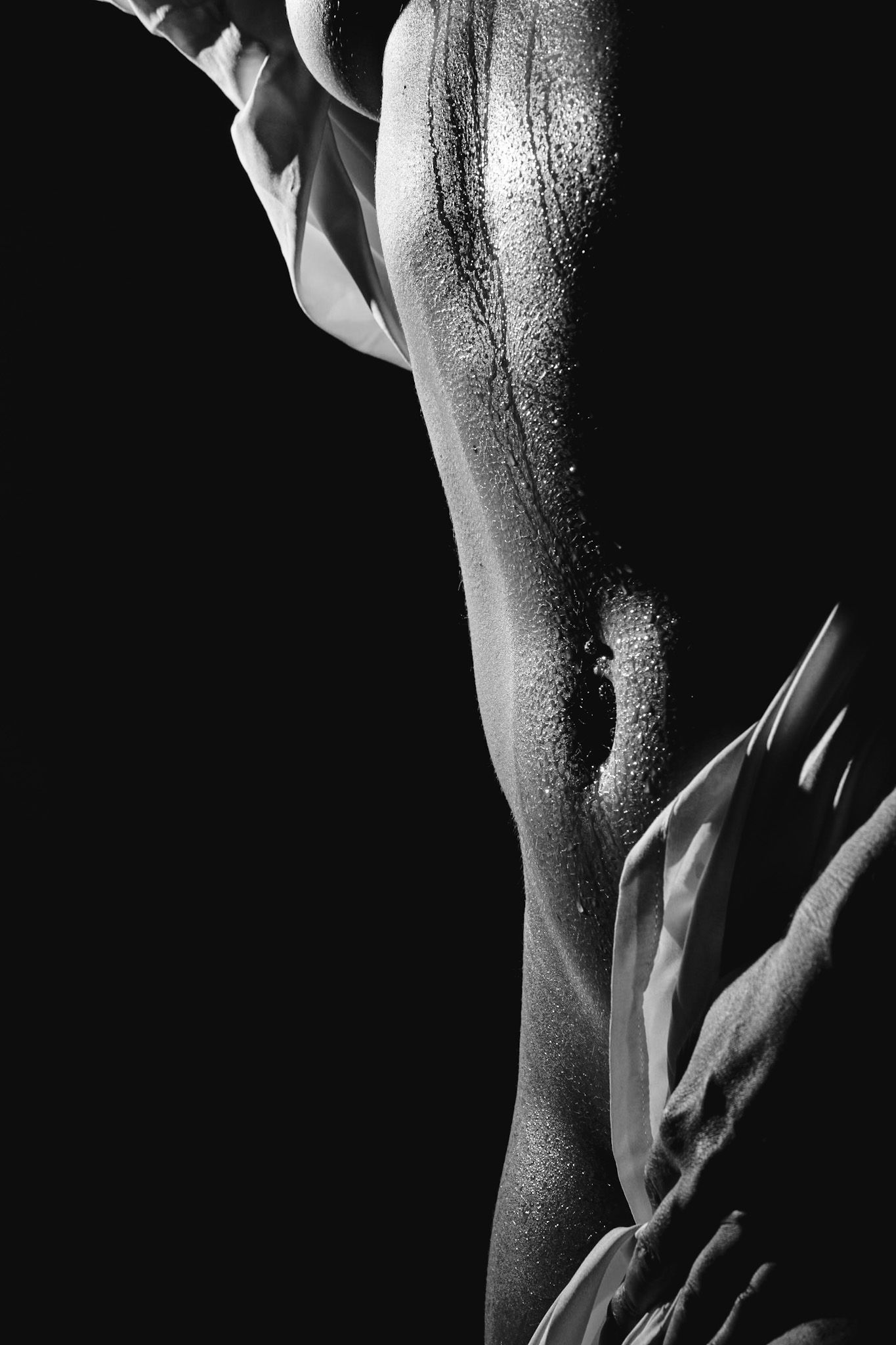 Artistic black and white close-up photograph showing an abstract curve with dramatic shadows and moisture droplets.
