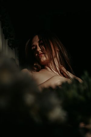 Ethereal portrait with soft natural lighting and bokeh through foliage.