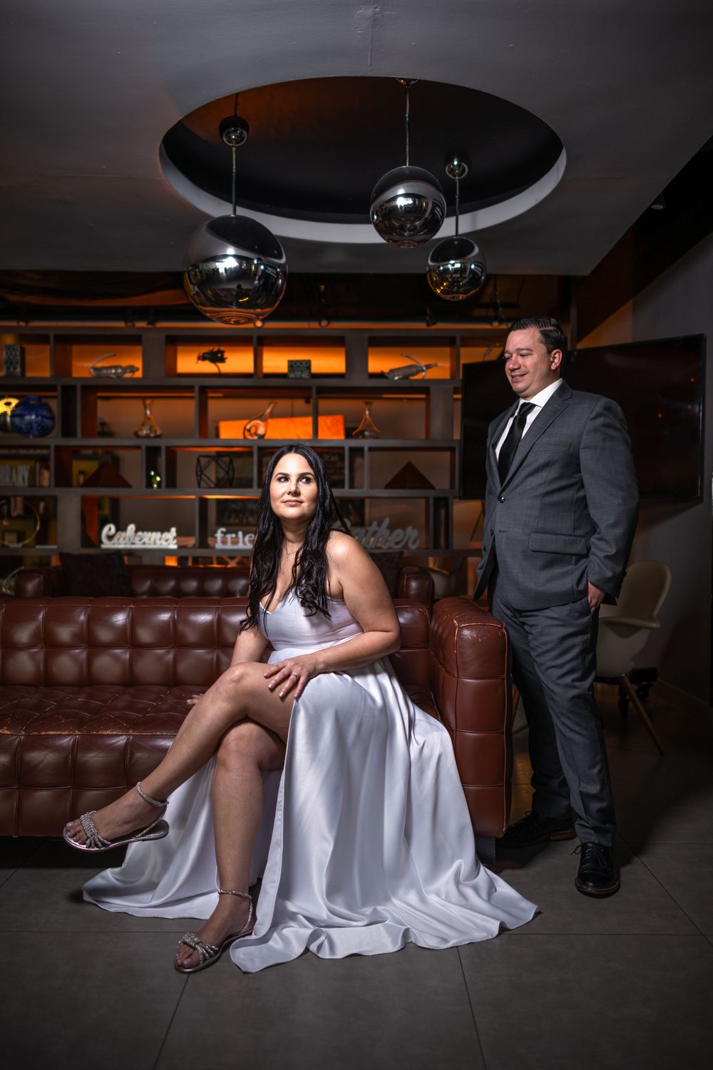 A glamorous couple poses in an upscale lounge with disco balls overhead.