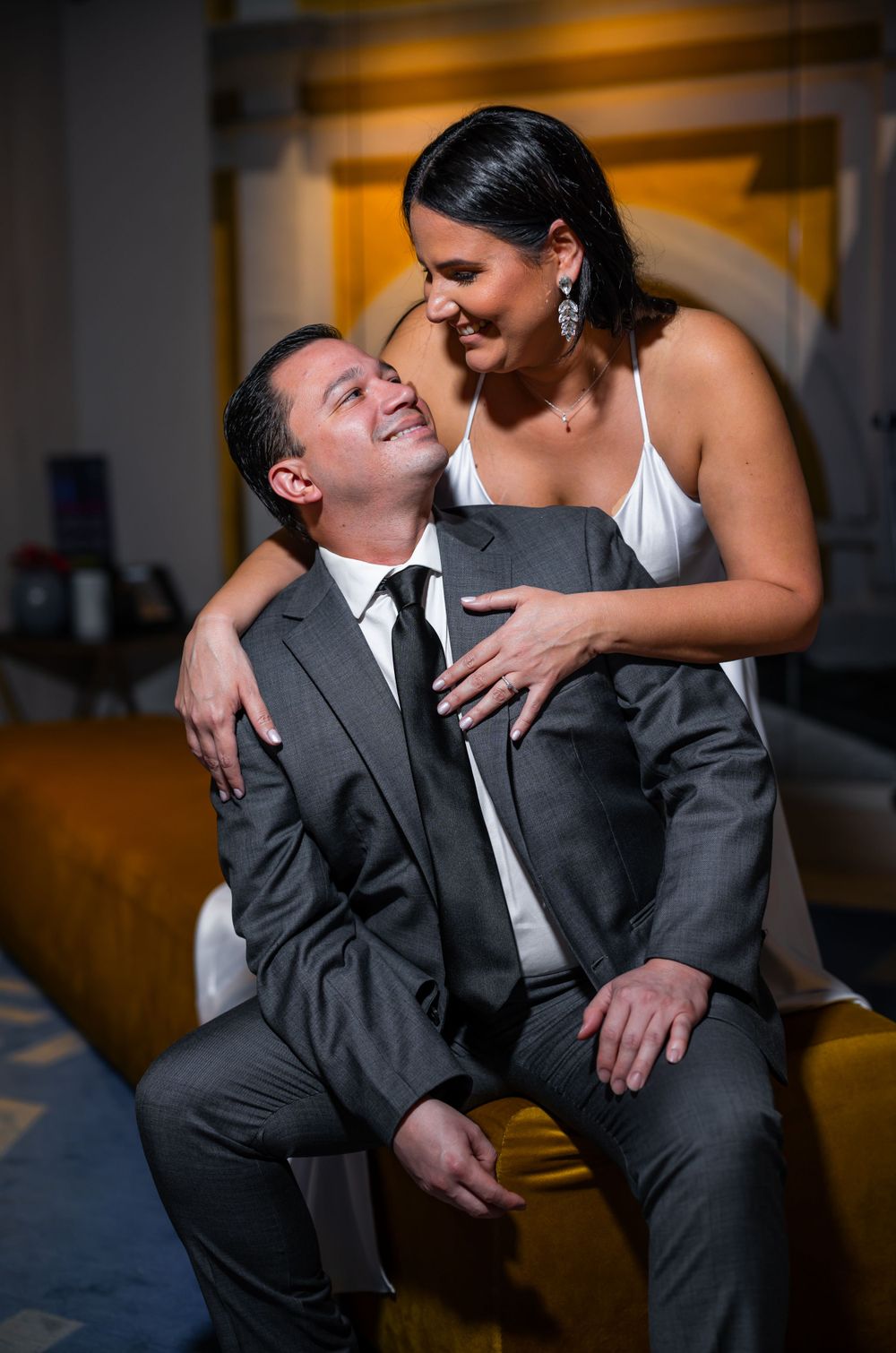 A couple shares a candid laughing moment in formal attire.