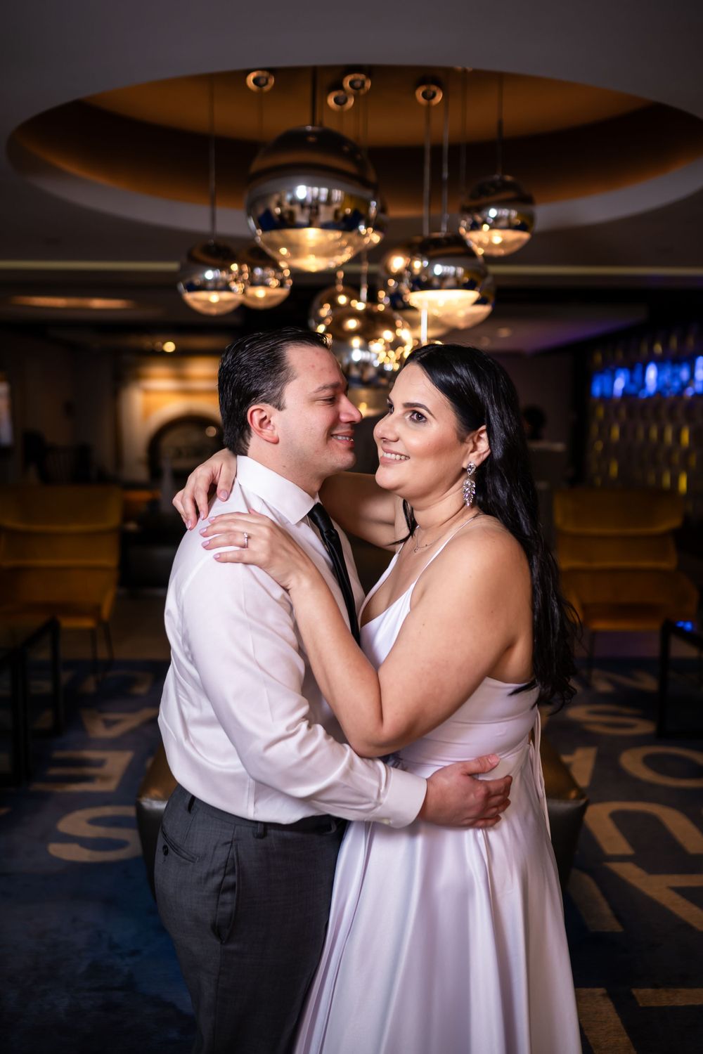 Romantic dance moment captured under elegant ceiling lights at wedding reception.