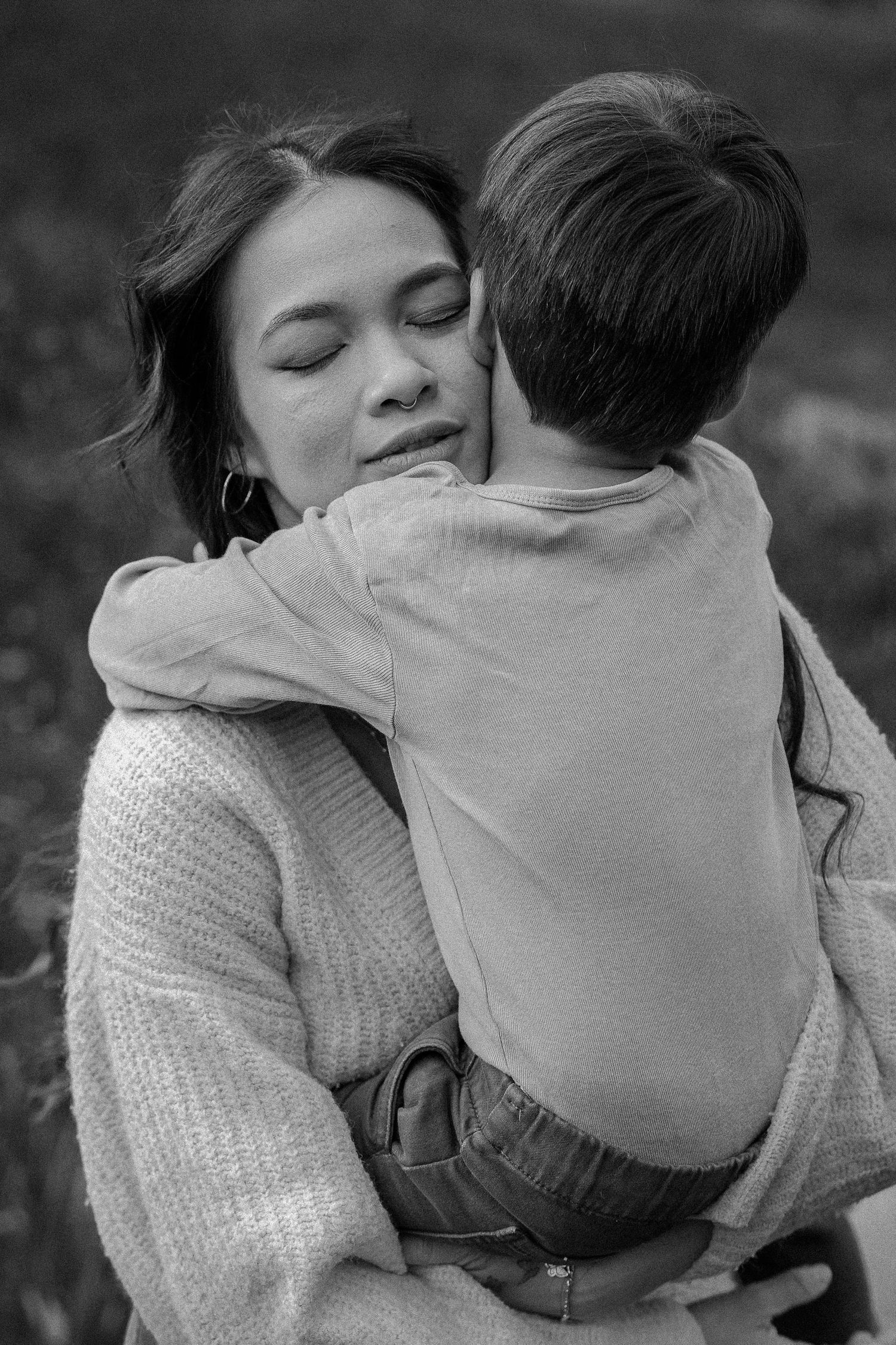 An intimate black and white portrait capturing a tender embrace between parent and child.