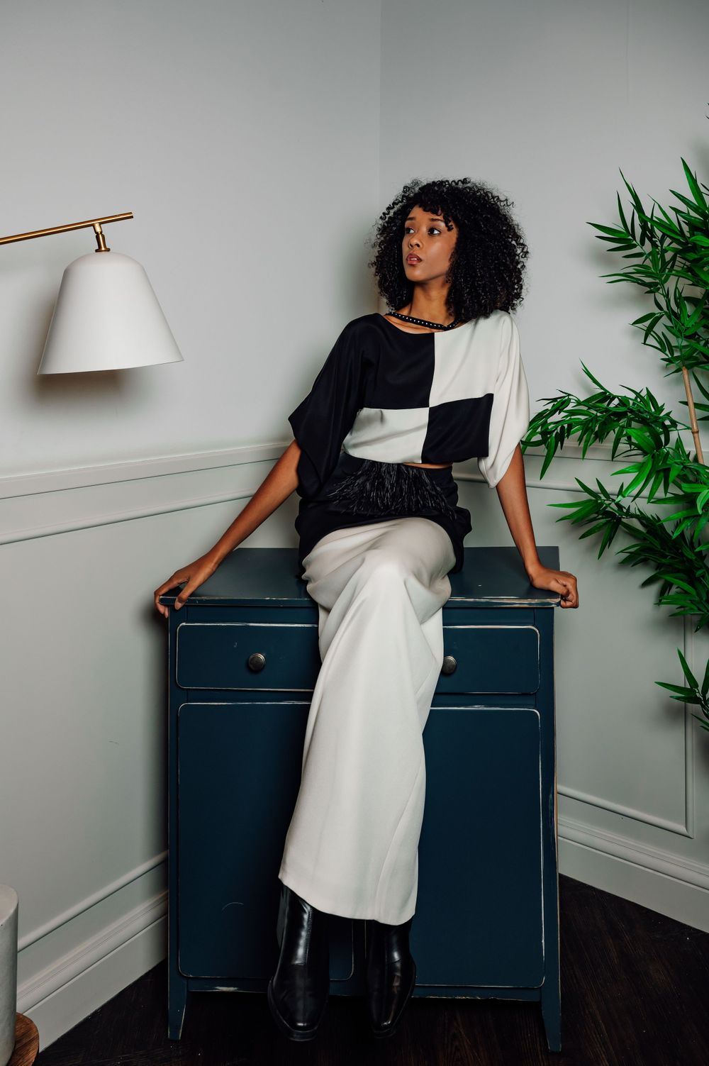 Minimalist fashion photography featuring contrasting black and white outfit against modern interior setting.