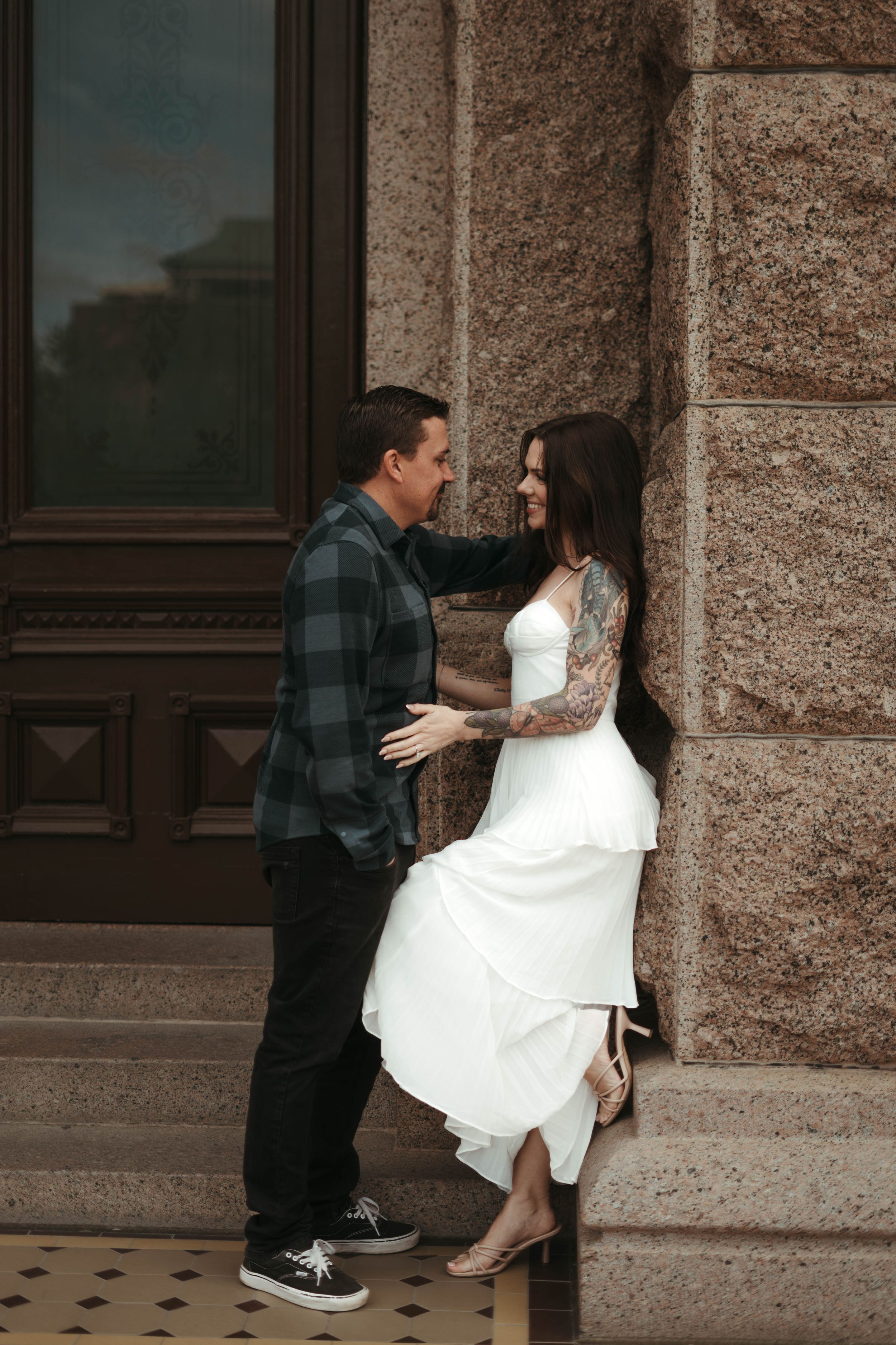 Intimate moment shared between couple against stone wall and wooden doors.