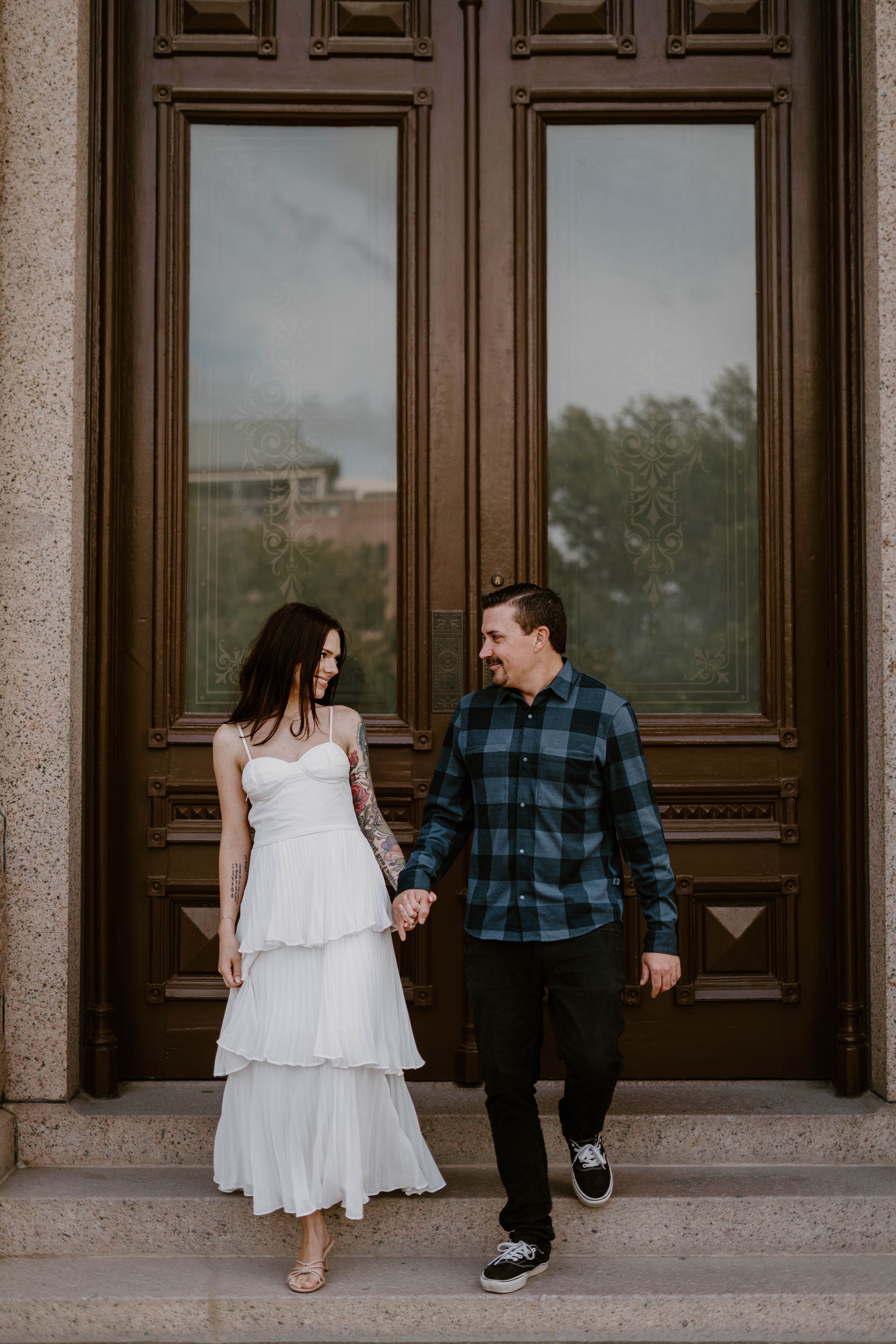 Couple sharing a romantic moment in front of grand wooden doors at a historic building.