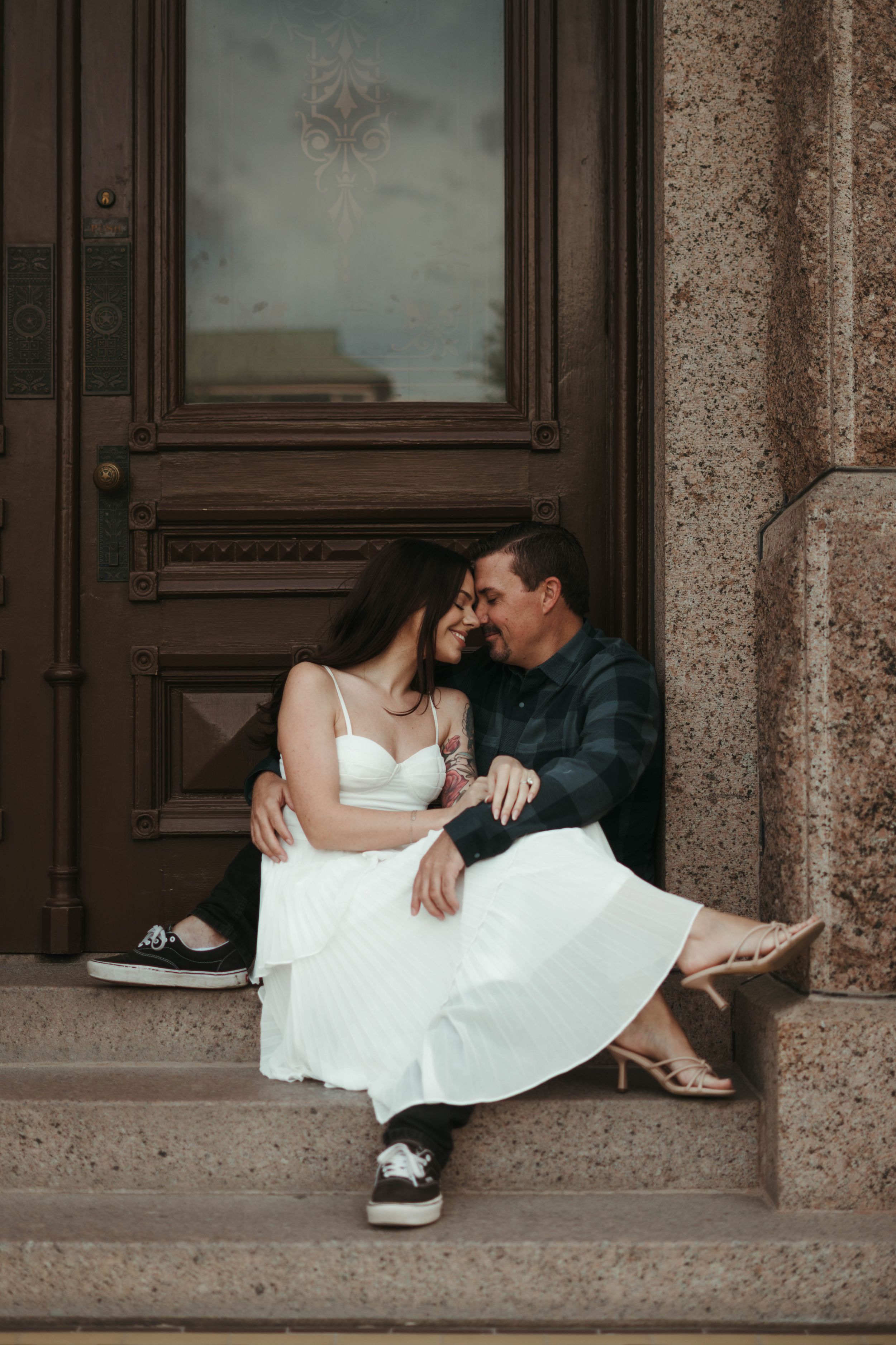 Romantic moment shared on stone steps in front of vintage wooden door.
