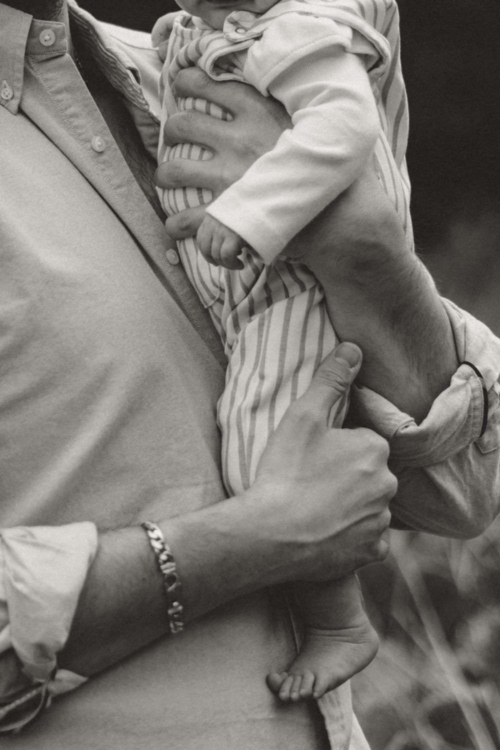 Black and white image of parent holding child in striped outfit.