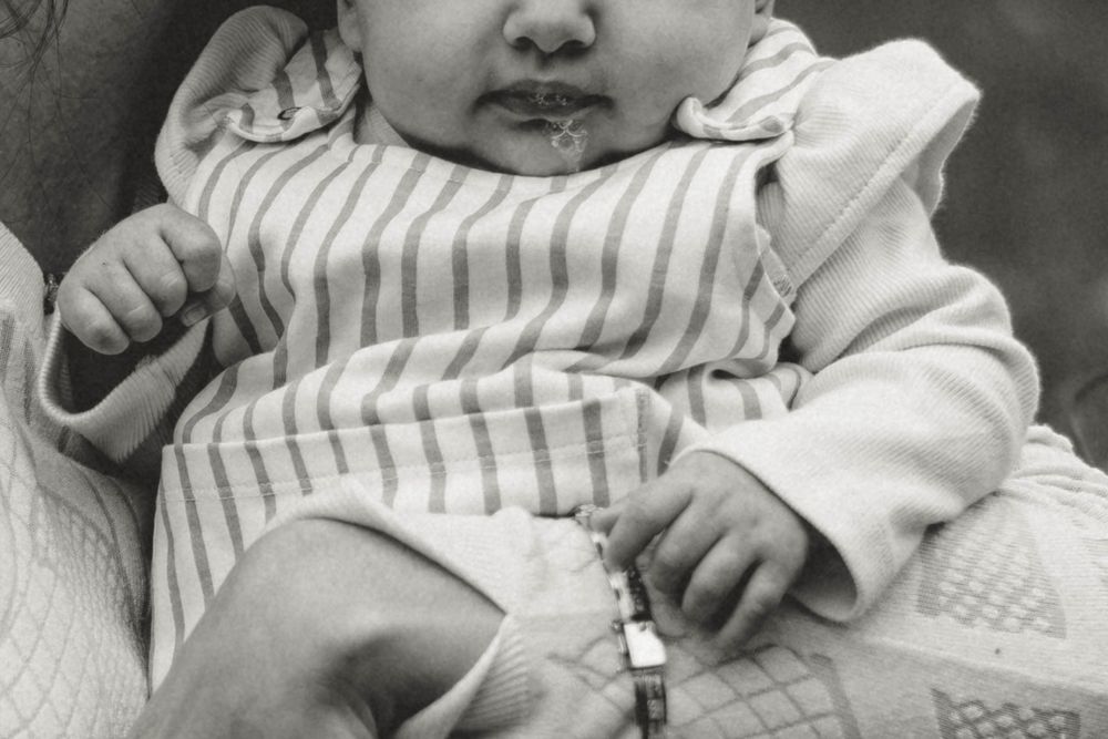 Close-up black and white portrait of infant in striped clothing.