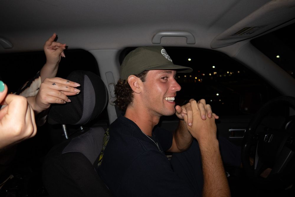 People laughing and celebrating inside a dimly lit car at night.