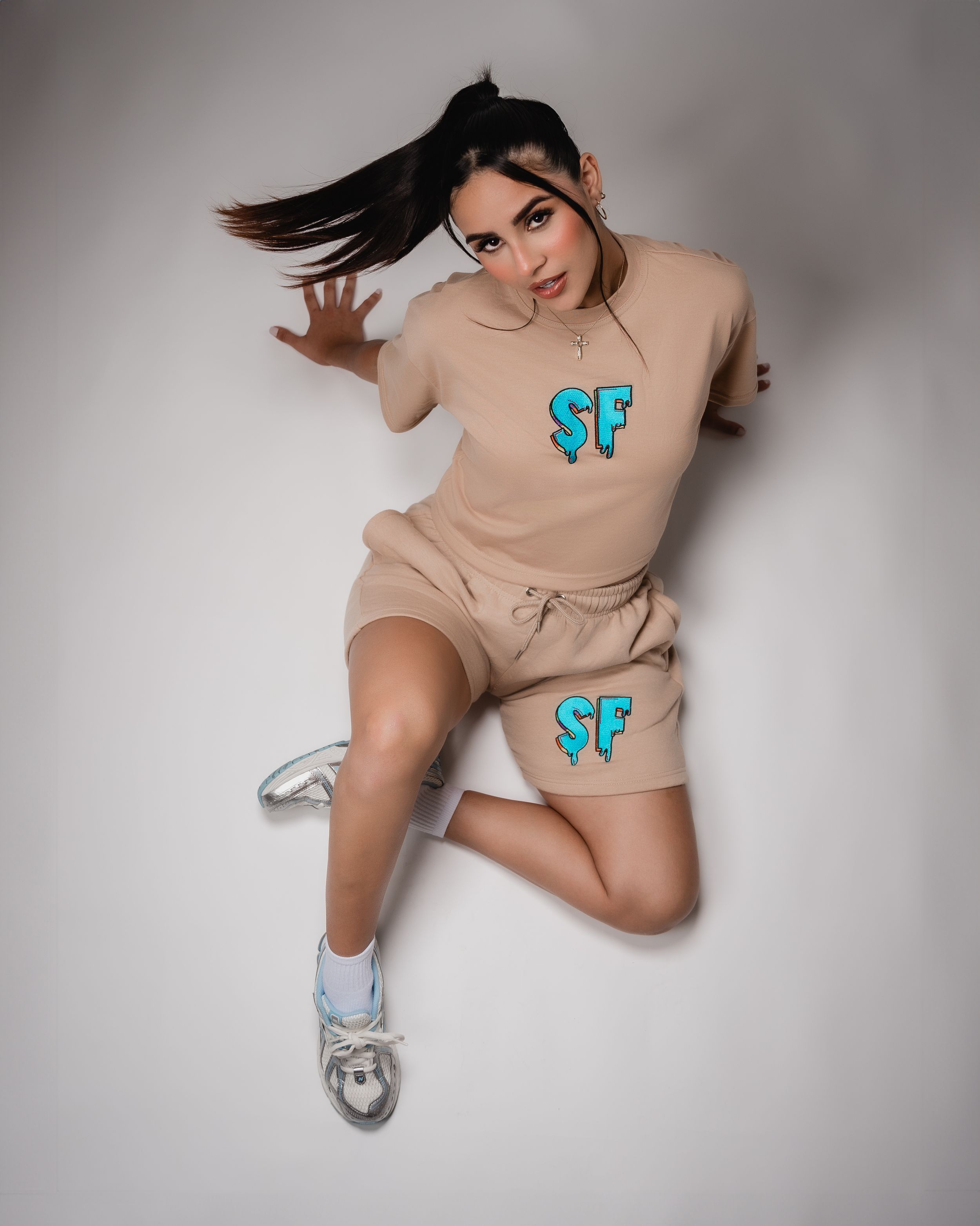 Dynamic fashion photo of beige activewear with teal SF logo.