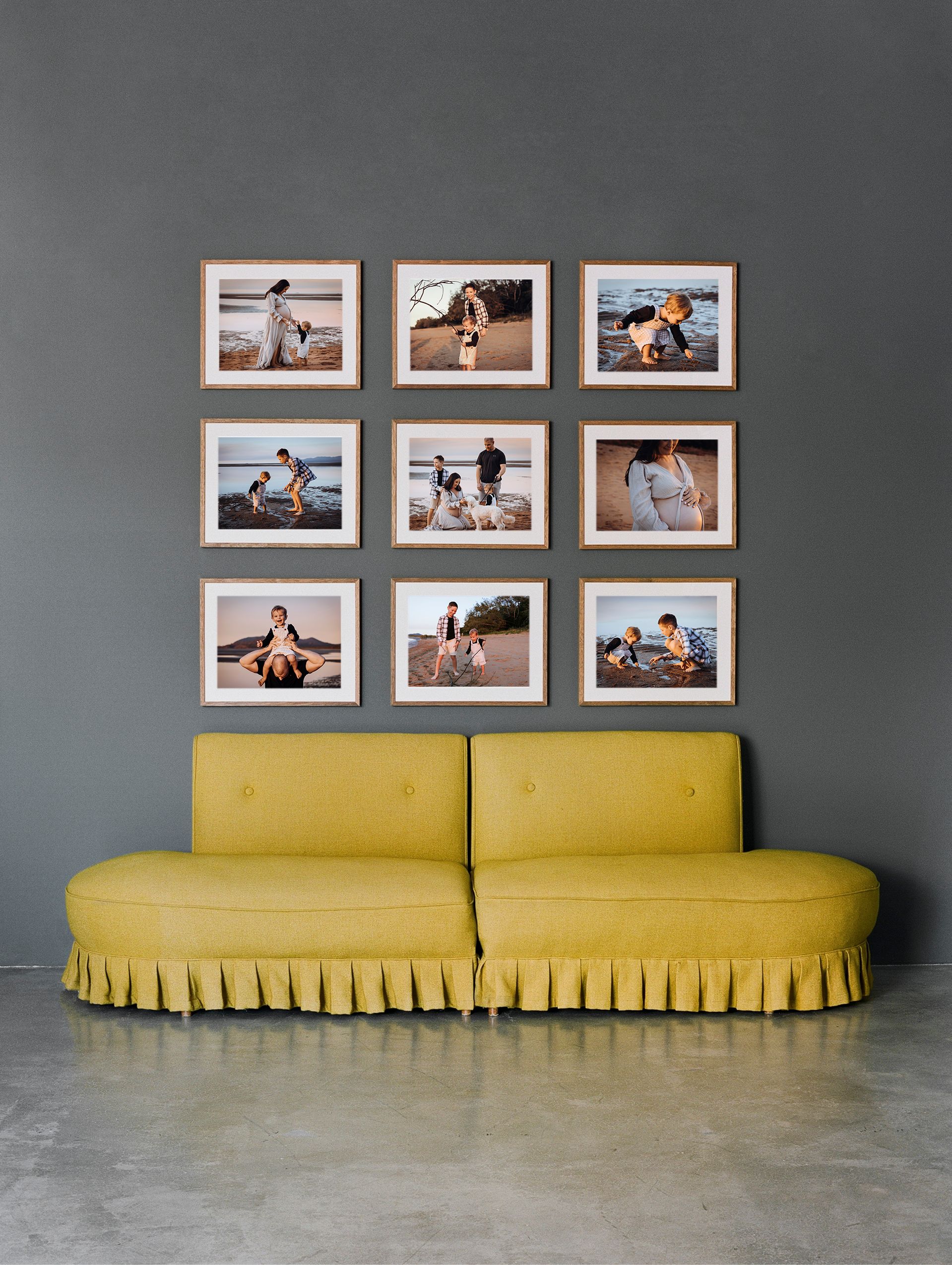 Nine framed photographs arranged in a grid above a yellow pleated sofa against a gray wall.