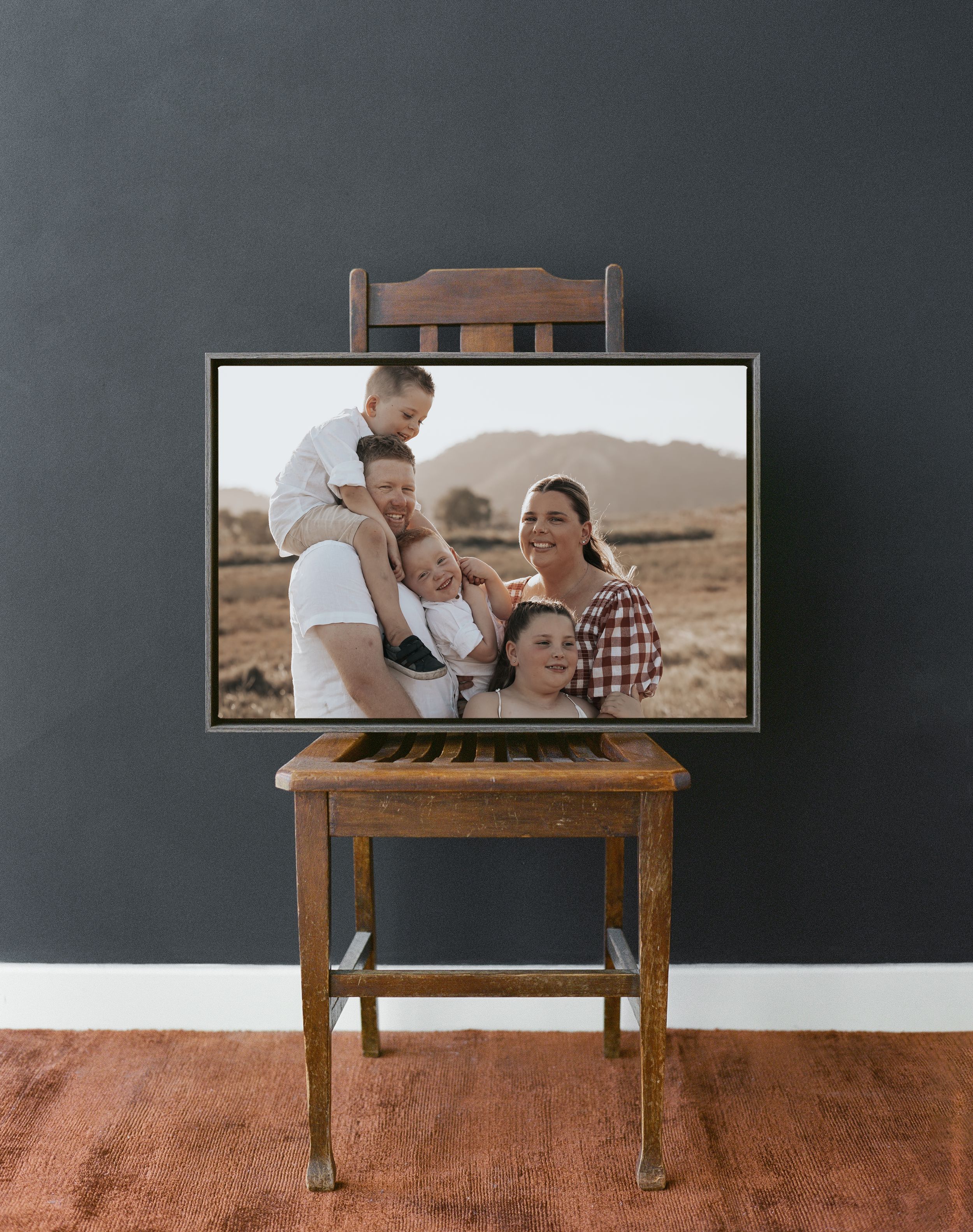 A framed photograph displayed on a vintage wooden chair against a dark gray wall.