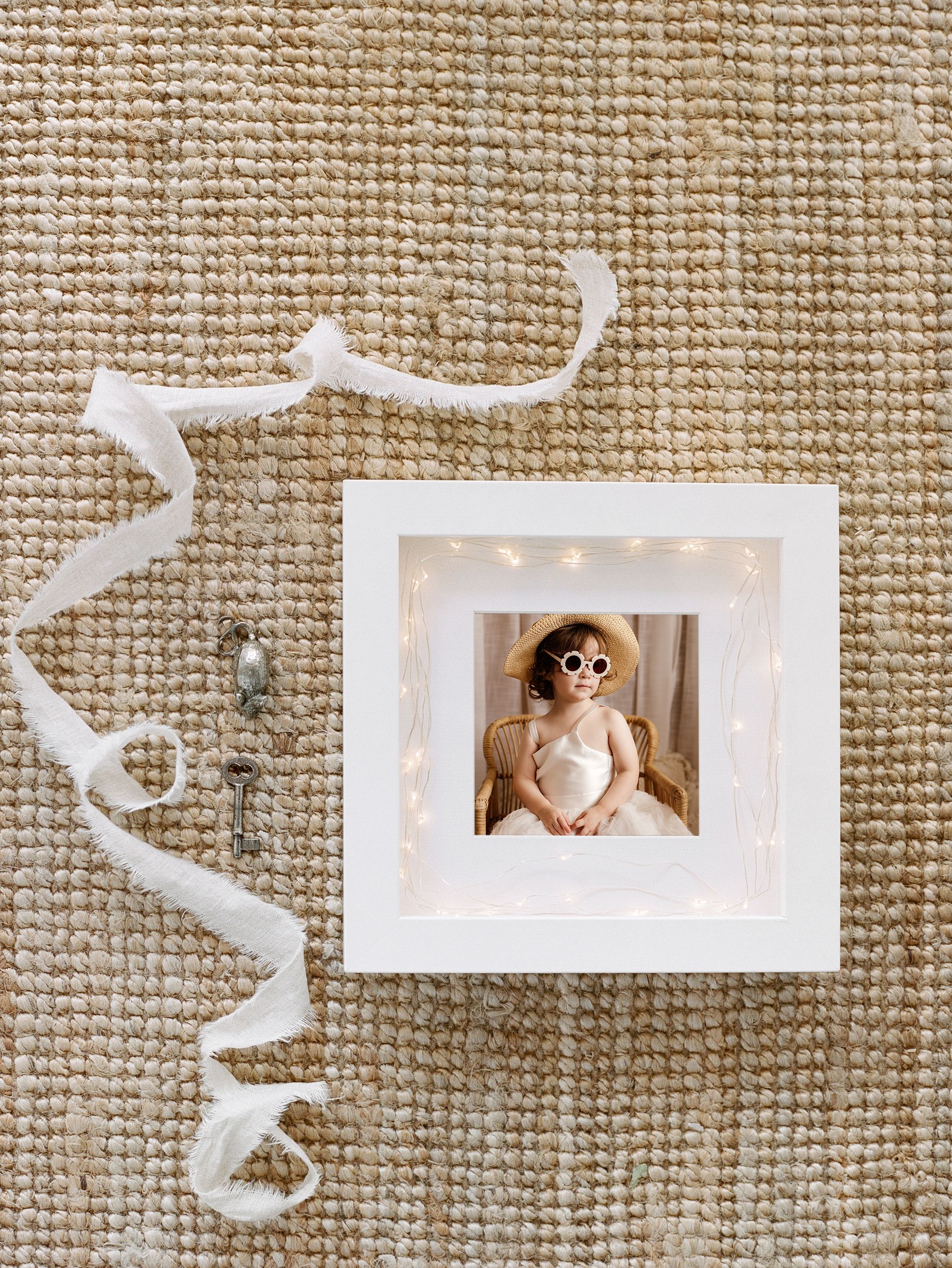 White photo frames with ribbon decorations arranged on textured burlap background.