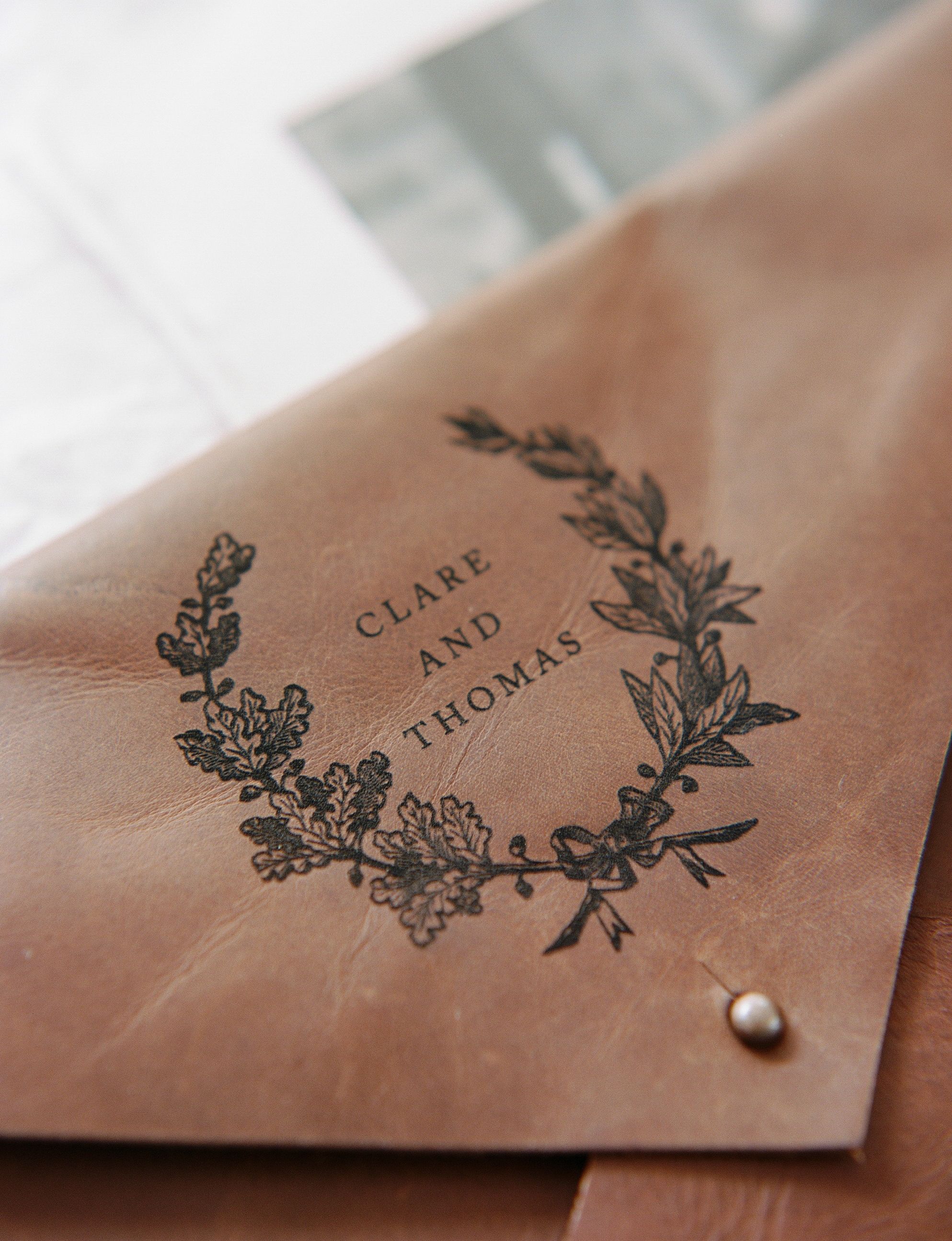 Close-up of brown leather envelope with floral design and text details.