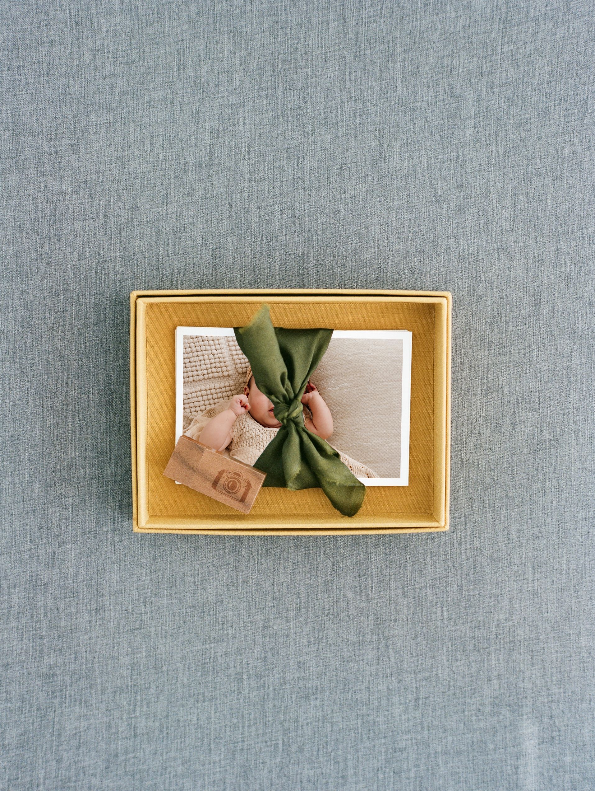 Minimalist display of golden box frames on gray textile background.