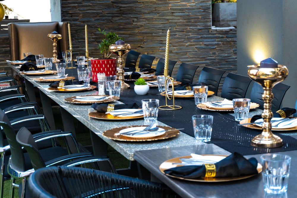 Elegant table setting with gold chargers, black plates, and candlesticks at a formal dinner event.