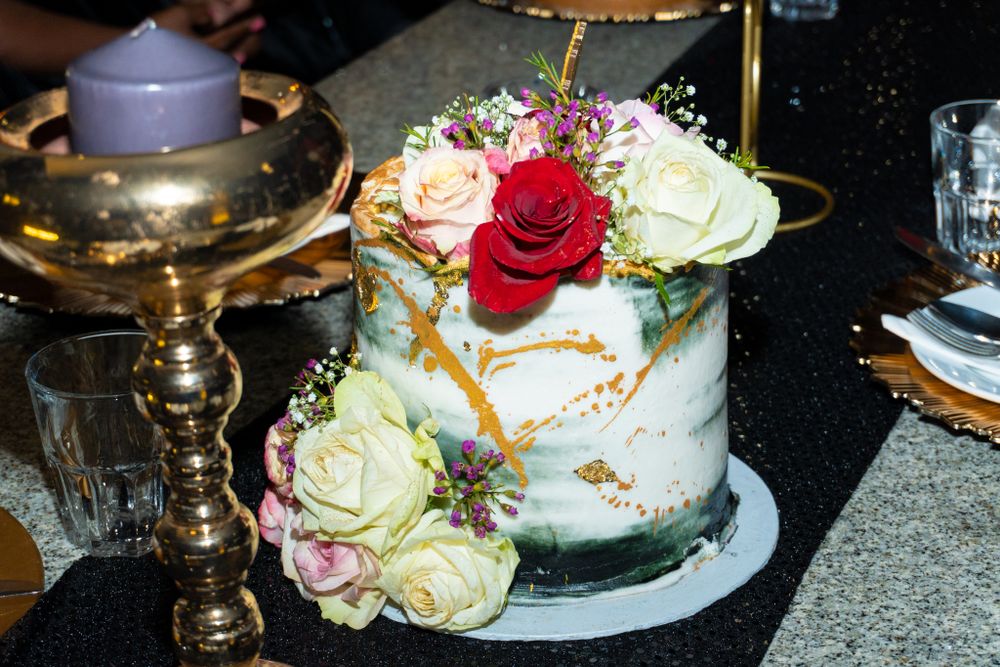 Beautiful white and gold marble cake decorated with fresh roses and floral accents.
