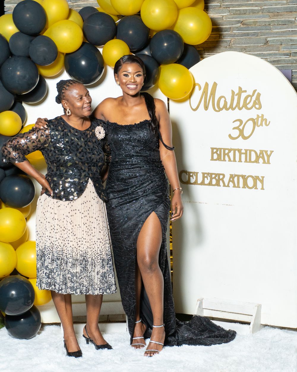 30th birthday celebration with black and gold balloon arch and elegant formal attire.