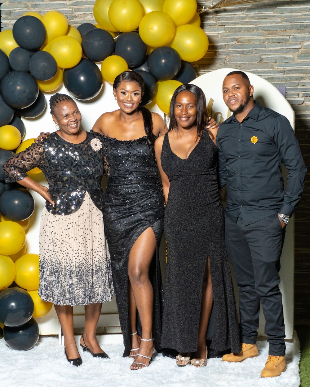 Group photo at Mottie's 30th birthday with black and gold balloon decorations.
