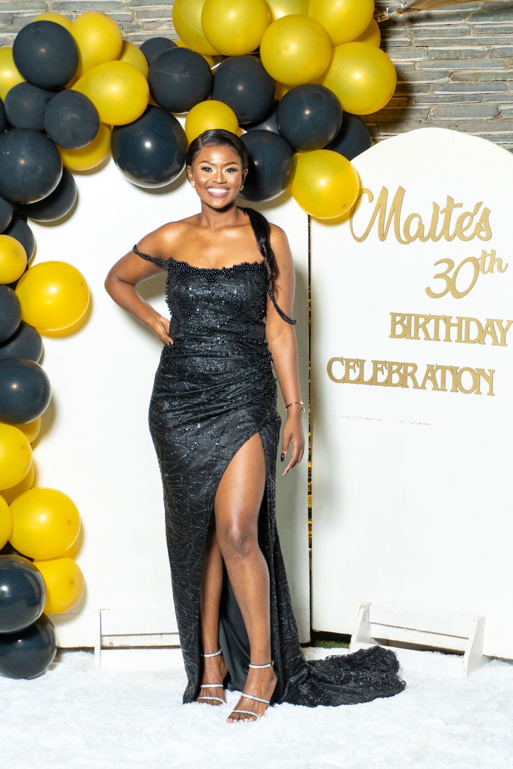 Elegant birthday photo setup with black and gold balloons and decorative text display.