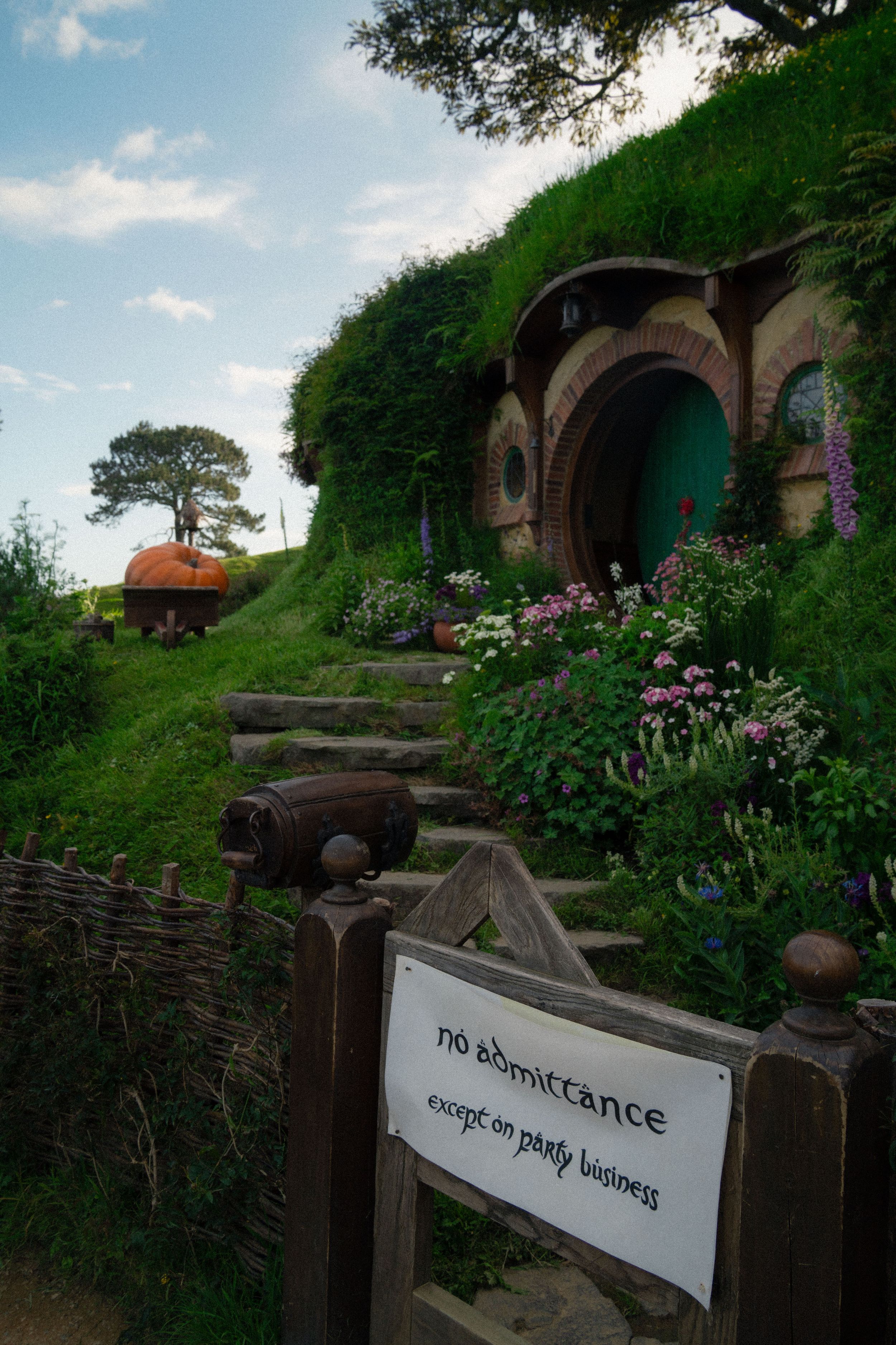 A winding path leads past hobbit homes with 'No Admittance' sign visible in the garden.