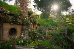 Charming hobbit holes with round doors surrounded by lush gardens and flowers in Hobbiton.