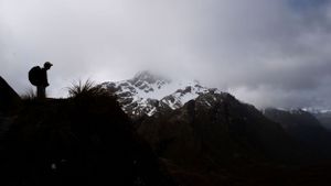 Silhouetted mountain peaks against cloudy sky at dusk.