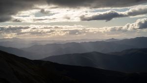 Dramatic mountain landscape with layered ridges and moody clouds during golden hour.