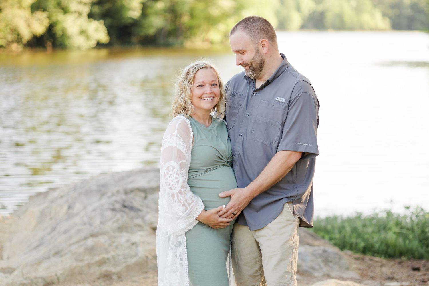 Couple embracing near a tranquil lake with beautiful sunset lighting.
