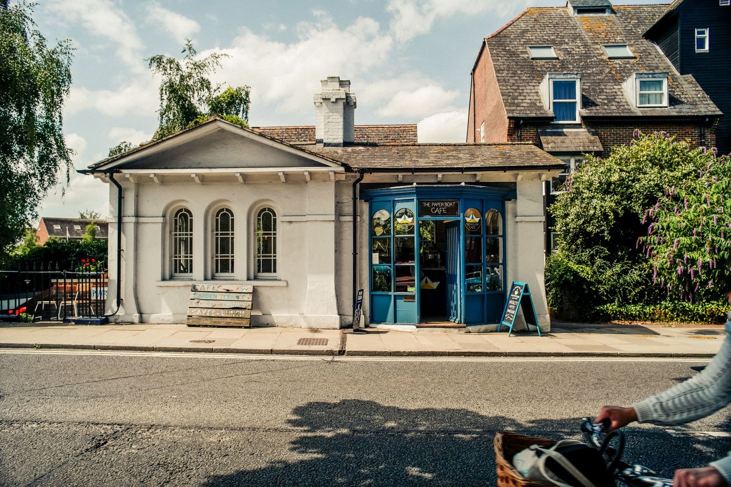 Small neoclassical building with arched windows and a blue door entrance on a quiet street.