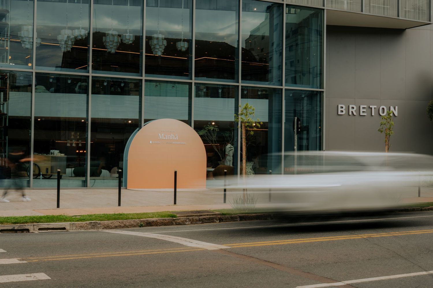 Modern storefront exterior of Breton building with glass windows and a peach-colored architectural detail.