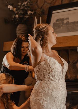 Close-up of the bride's dress being buttoned by her mother.