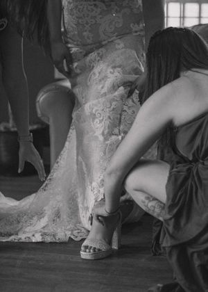 Close-up of the bridal party helping the bride put on her shoes, highlighting the shoe details.