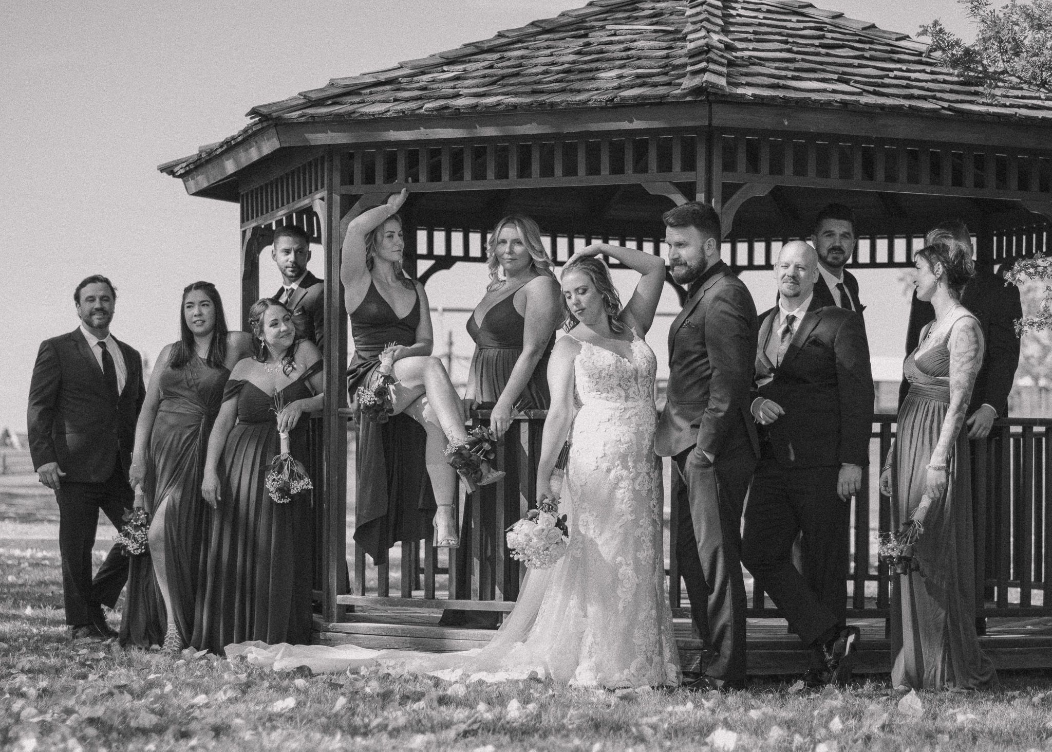 Trendy wedding party poses around a gazebo, exuding stylish, Vogue-like vibes captured in timeless black and white.