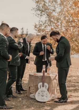 Groomsmen enjoying drinks and cigars, capturing a relaxed and celebratory moment together.
