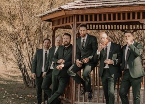 Groom and groomsmen posed together under a gazebo, surrounded by vibrant fall foliage.