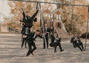 Groom and groomsmen joyfully playing on swings, capturing playful wedding moments.