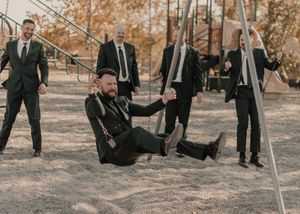 Groom and groomsmen joyfully playing on swings, capturing playful wedding moments.