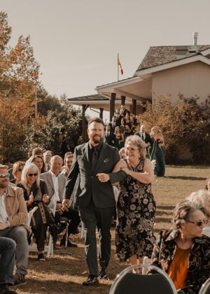 Groom and mother walking down the aisle together, sharing a heartfelt moment at the wedding ceremony.